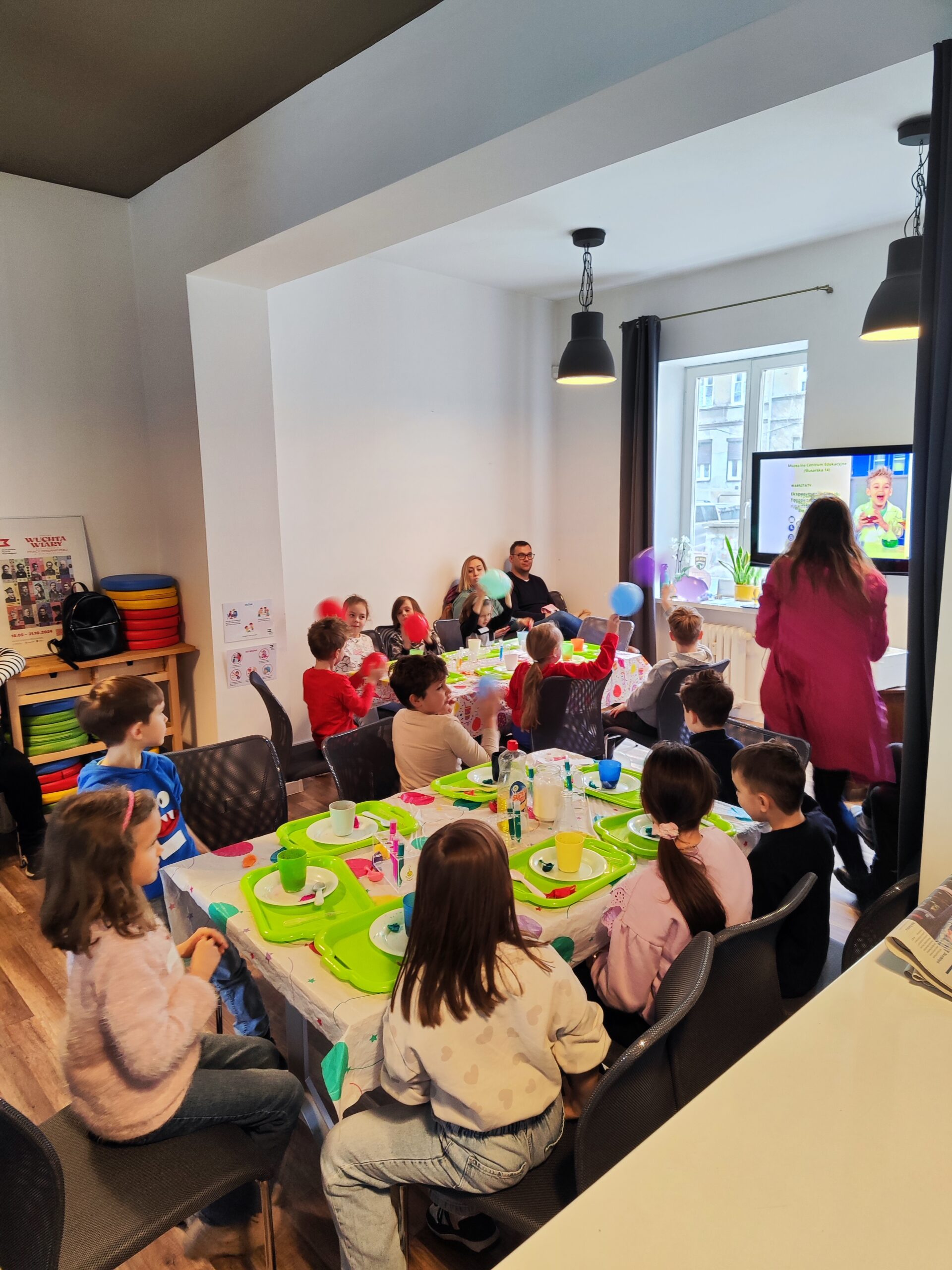 Zdjęcie z warsztatów pod tytułem „Eksperymenty Stasia Taczaka, czyli chemia dla każdego ejbra” Na zdjęciu widzimy grupkę dzieci eksperymentujących z suchym lodem.