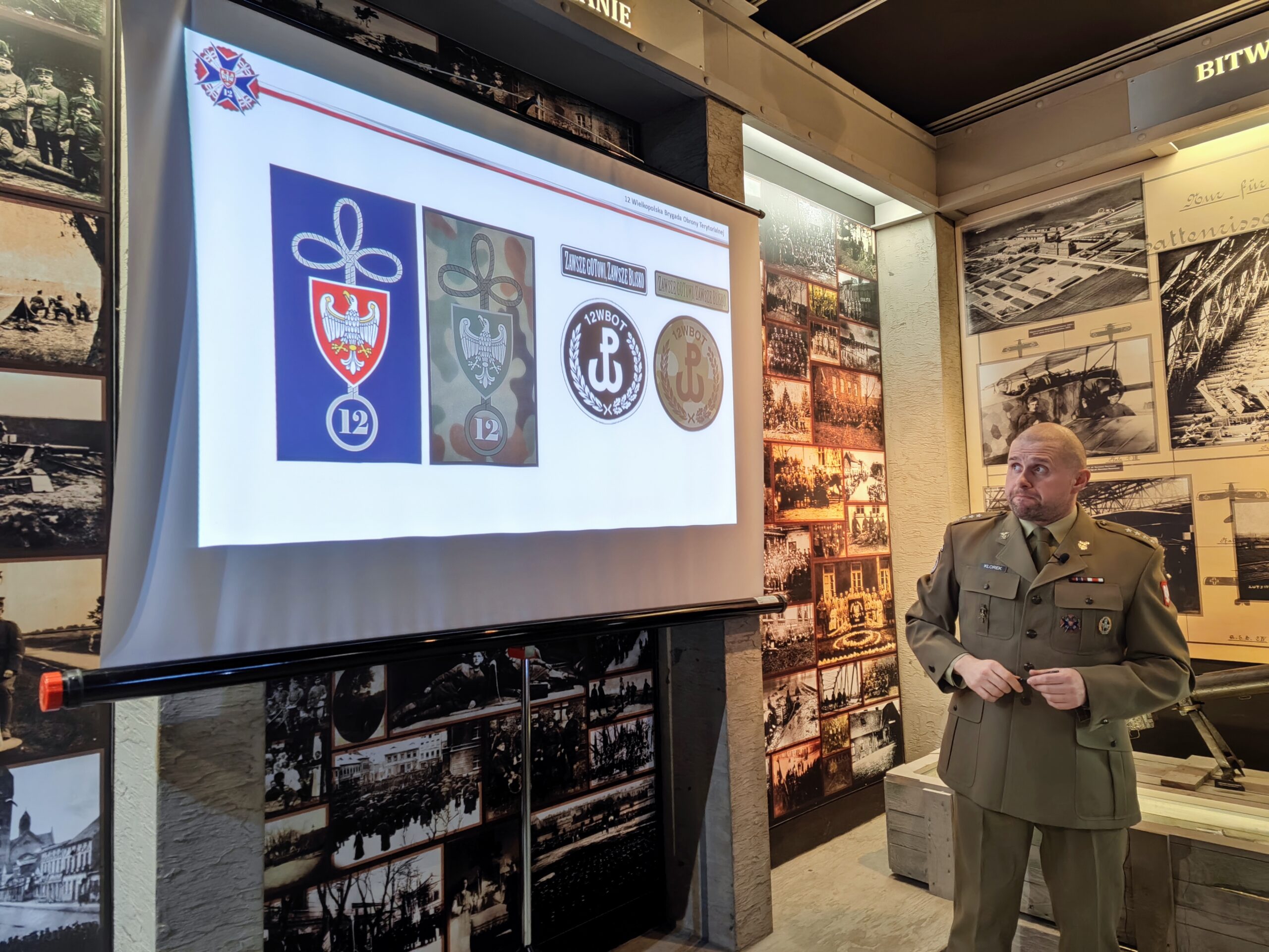 Zdjęcie przedstawia prelekcje w Muzeum Powstania Wielkopolskiego 1918-1919. Prowadzący opowiada o aktualnie wyświetlonym slajdzie prezentacji.