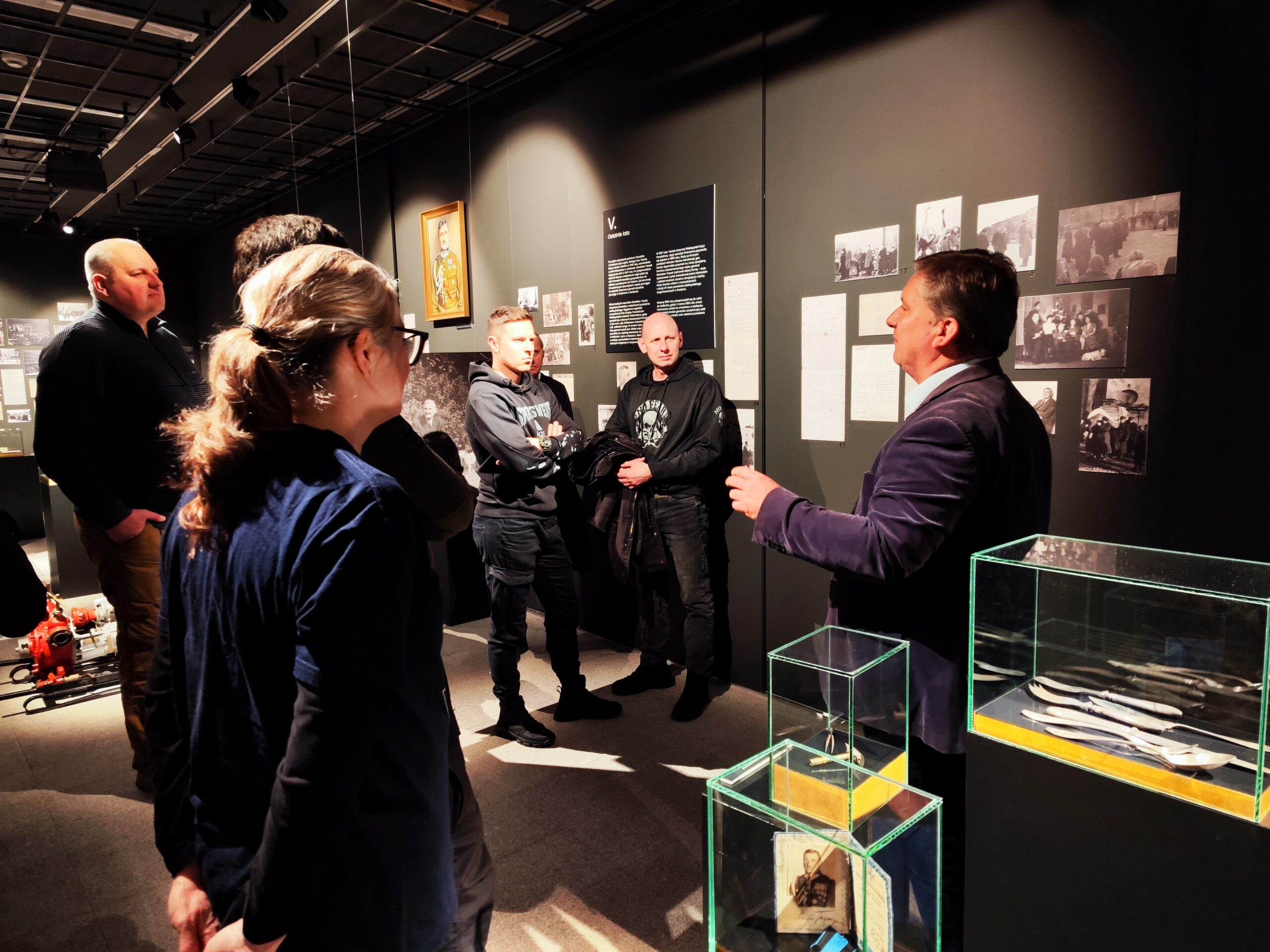 Zdjęcie przedstawia grupę osób zwiedzających wystawę czasową „Generał Stanisław Taczak - naukowiec, dowódca, społecznik” w Muzeum Powstania Wielkopolskiego 1918-1919 z przewodnikiem.