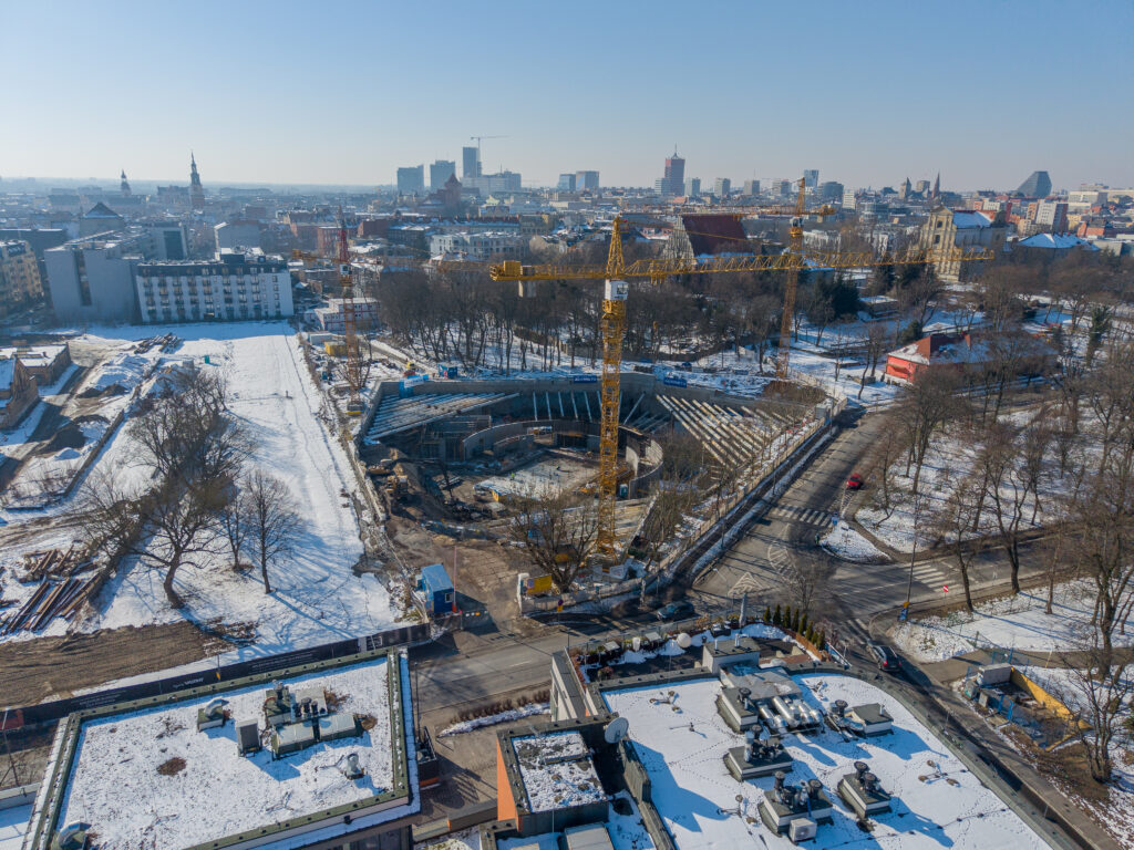 Na fotografii z lotu ptaka widzimy plac budowy nowego budynku Muzeum Powstania Wielkopolskiego 1918-1919. W centrum widzimy żółtego żurawia oraz podpory ścienne.